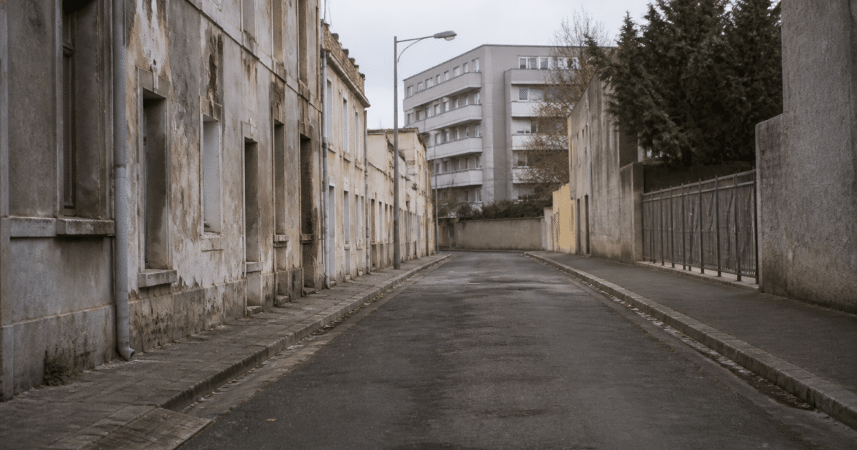 Rue déserte de Drancy avec immeubles gris et bâtiments délabidés