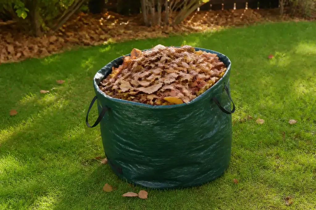 Grand sac vert rempli de feuilles sur la pelouse
