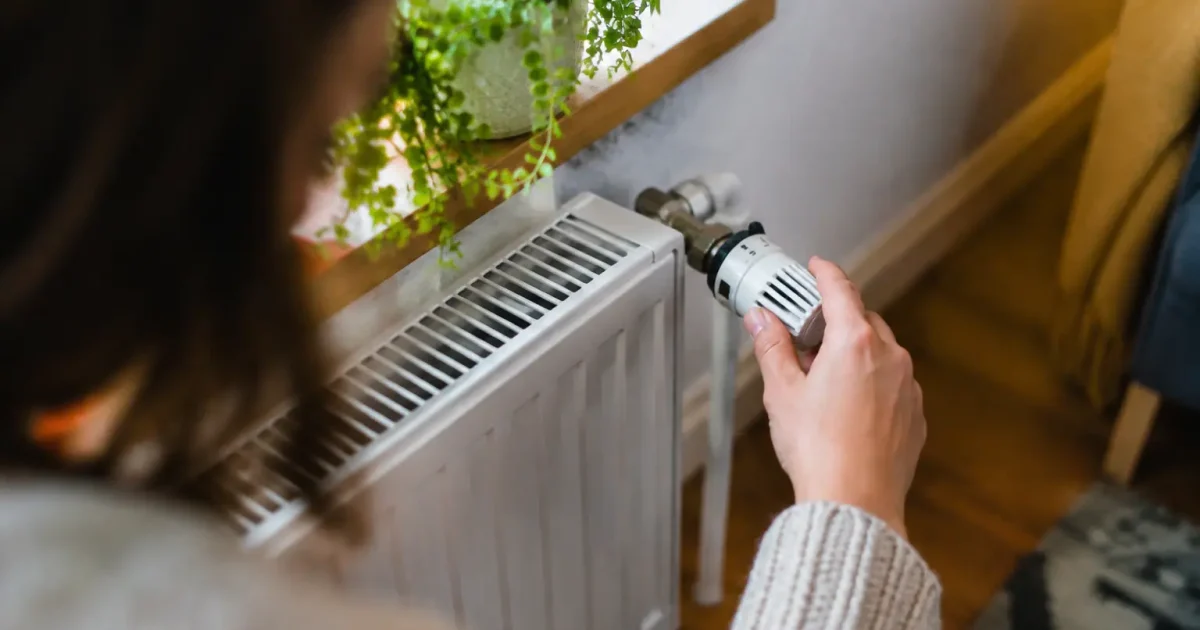 Main tournant une vanne thermostatique sur radiateur blanc