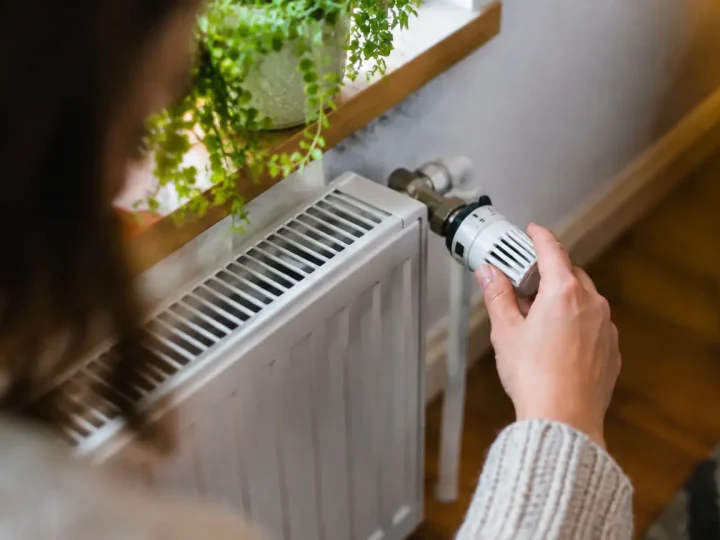 Main tournant une vanne thermostatique sur radiateur blanc