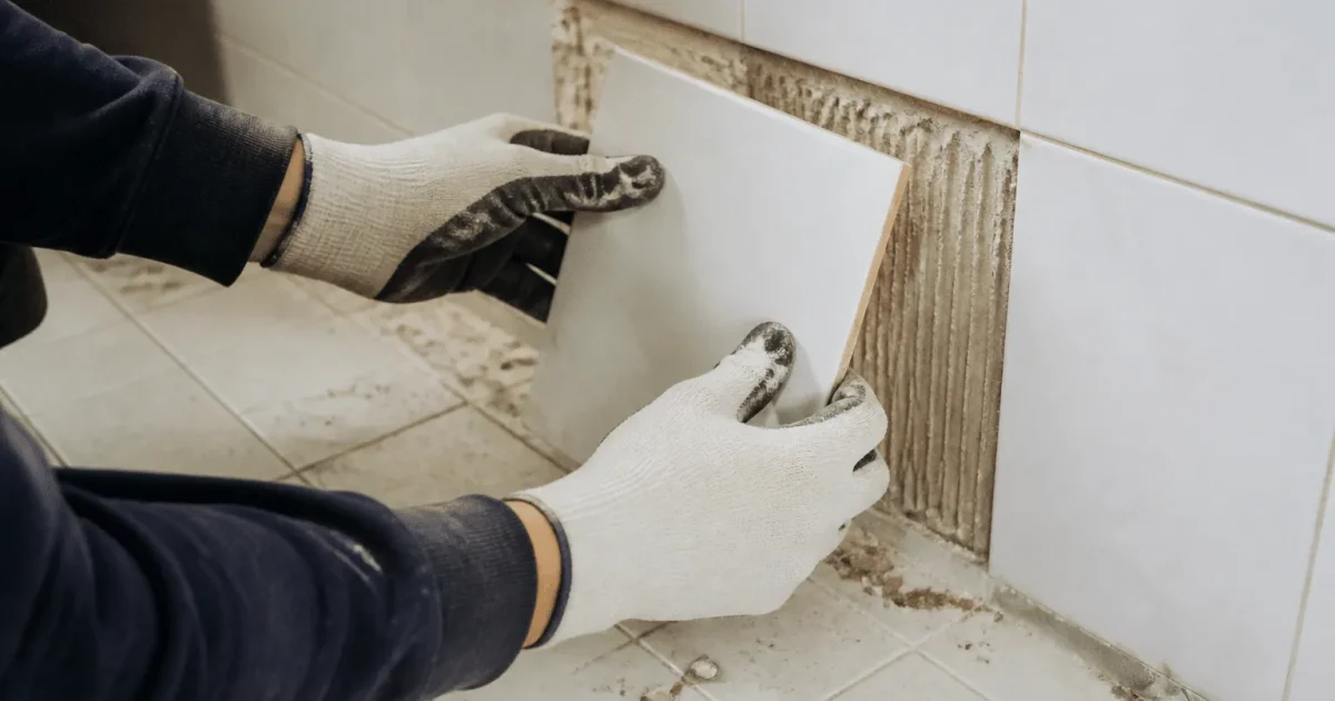 Mains gantees soulevant carrelage blanc du sol mur