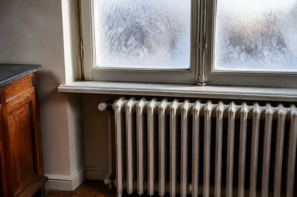 Radiateur en fonte sous une fenetre givree