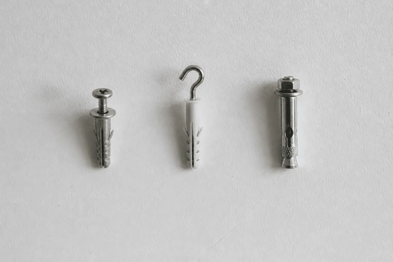Trois outils de fixation alignes sur surface murale blanche